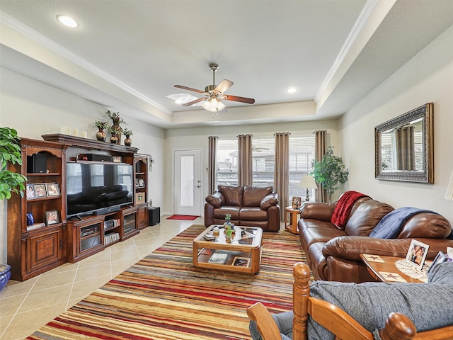 living room featuring a raised ceiling, ceiling fan, light tile patterned flooring, and crown molding