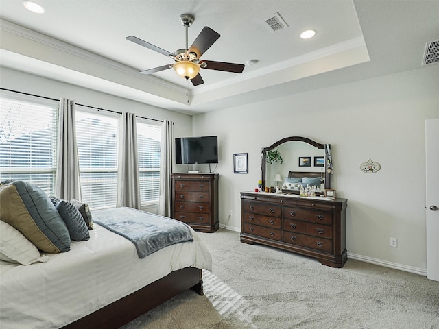 carpeted bedroom with ceiling fan, a tray ceiling, and crown molding