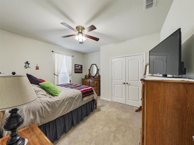 bedroom with ceiling fan, a closet, and light colored carpet