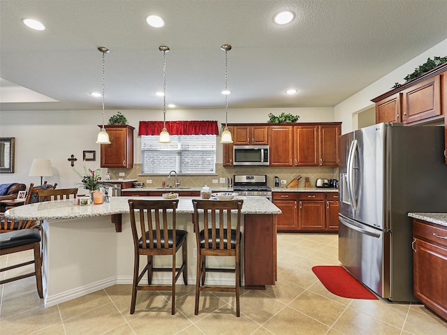 kitchen with decorative light fixtures, decorative backsplash, stainless steel appliances, and a kitchen island