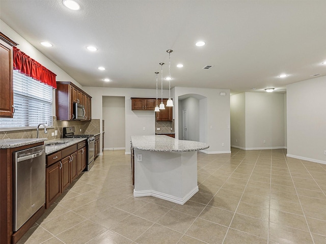 2337 Brookdale Dr, Frisco, TX 75036 - kitchen with stainless steel appliances, decorative backsplash, recessed lighting, arched walkways, and a center island