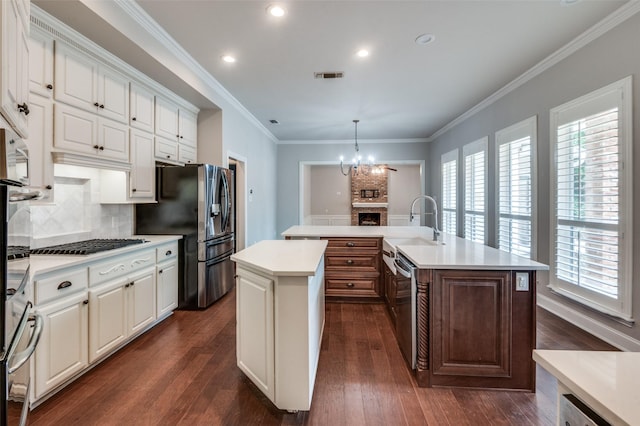 kitchen featuring pendant lighting, white cabinets, tasteful backsplash, an island with sink, and sink