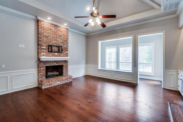 unfurnished living room featuring dark wood-type flooring, a tray ceiling, ornamental molding, and a fireplace