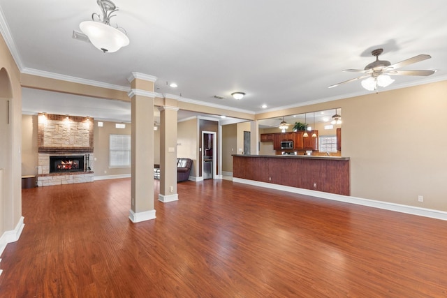 unfurnished living room with ornate columns, ornamental molding, ceiling fan, and a fireplace