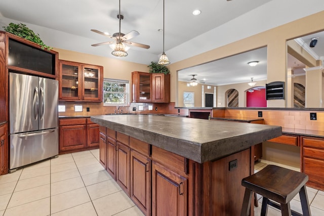 kitchen featuring light tile patterned flooring, stainless steel refrigerator, tasteful backsplash, a kitchen breakfast bar, and a center island