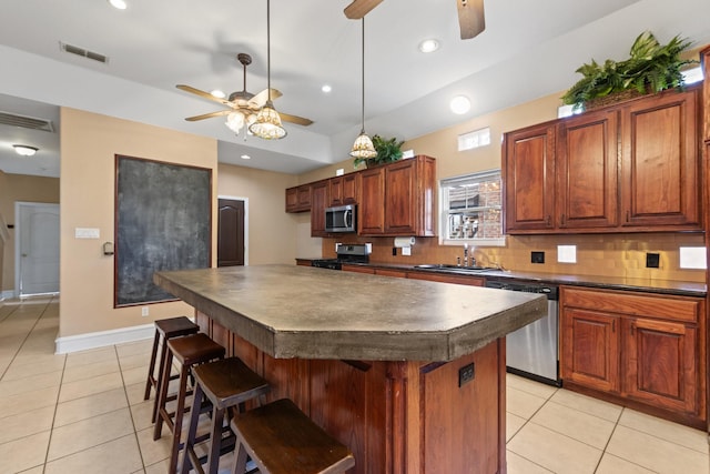 kitchen featuring sink, tasteful backsplash, a center island, appliances with stainless steel finishes, and a kitchen breakfast bar