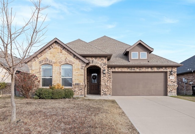 french provincial home with brick siding, roof with shingles, concrete driveway, and an attached garage