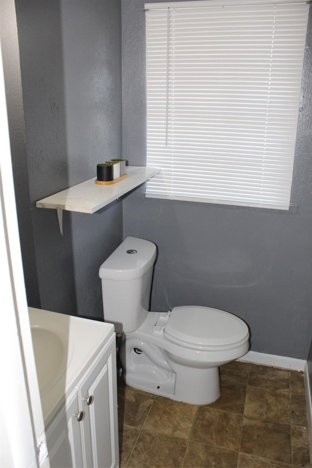 bathroom featuring toilet, vanity, and baseboards