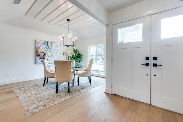 foyer with wood-type flooring, beamed ceiling, and an inviting chandelier