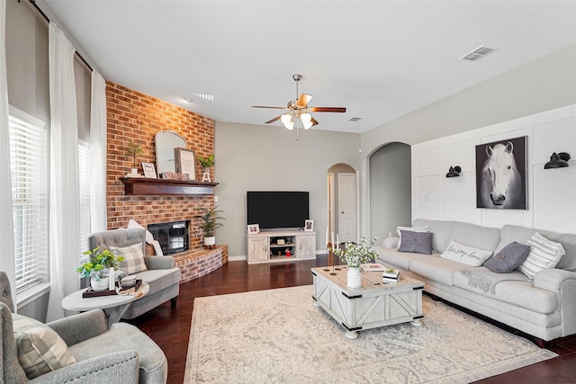 living room with dark hardwood / wood-style flooring, ceiling fan, and a fireplace