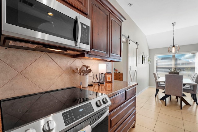 kitchen with light tile patterned floors, appliances with stainless steel finishes, hanging light fixtures, vaulted ceiling, and a barn door