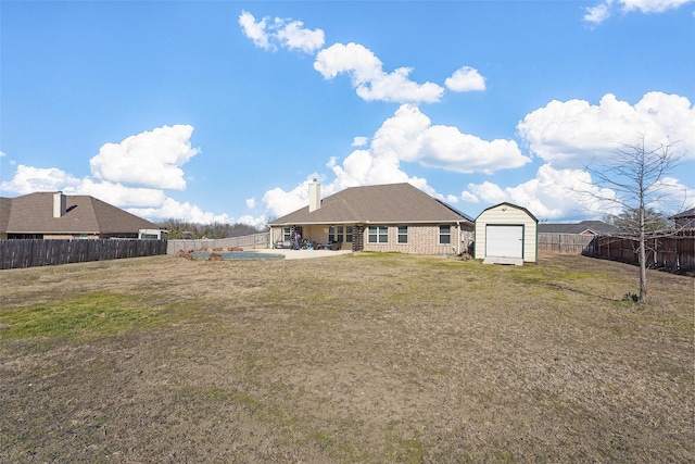 rear view of property featuring a pool, a storage unit, and a lawn