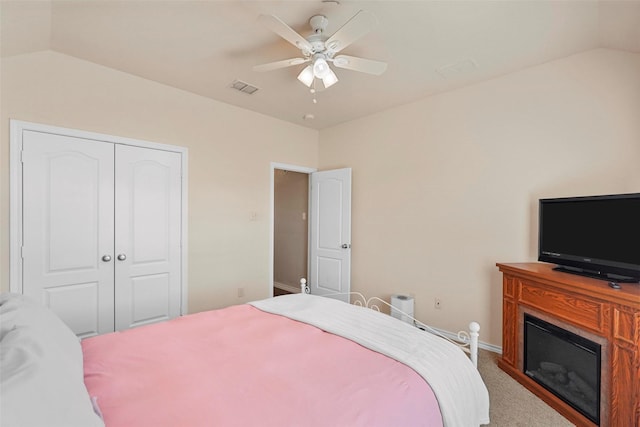 bedroom with vaulted ceiling, a closet, ceiling fan, and carpet flooring