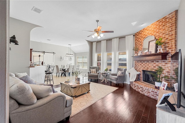 living room with vaulted ceiling, a brick fireplace, dark hardwood / wood-style floors, and ceiling fan