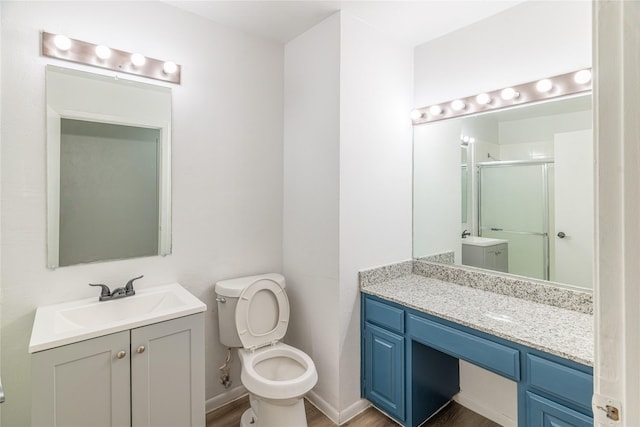 bathroom featuring hardwood / wood-style floors, toilet, a shower with door, and vanity