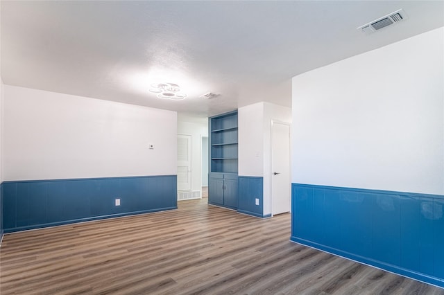 empty room with built in features and dark hardwood / wood-style floors