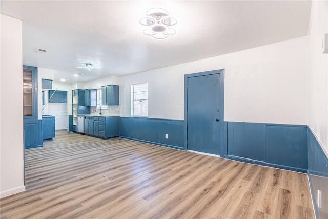 kitchen with light hardwood / wood-style flooring, blue cabinetry, tasteful backsplash, and sink