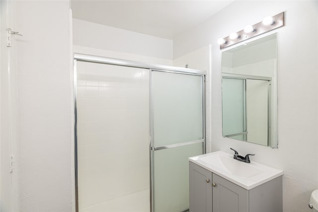 bathroom with toilet, a shower with door, and vanity