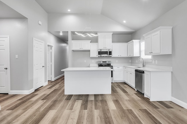 kitchen with a kitchen island, white cabinetry, stainless steel appliances, sink, and vaulted ceiling