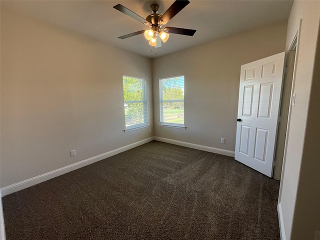 unfurnished room with ceiling fan and dark carpet