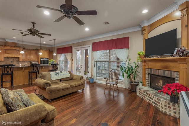 living room with dark hardwood / wood-style flooring, crown molding, a fireplace, and ceiling fan