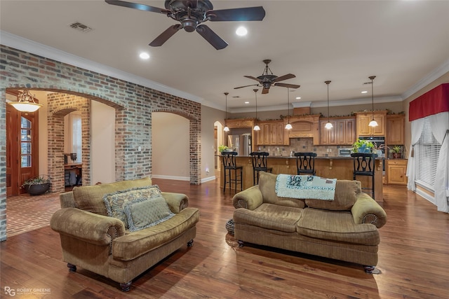 living room featuring crown molding, brick wall, ceiling fan, and dark hardwood / wood-style flooring