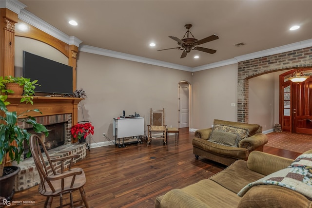 living room with ornamental molding, dark wood-type flooring, ceiling fan, and a fireplace