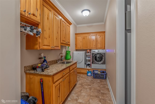 laundry area featuring cabinets, crown molding, washer and dryer, and sink