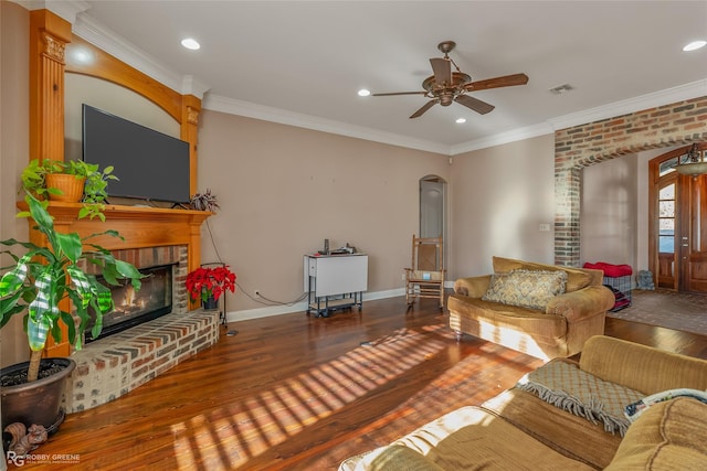 living room featuring crown molding, hardwood / wood-style floors, ceiling fan, and a fireplace