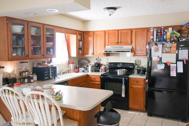 kitchen with a textured ceiling, black appliances, sink, kitchen peninsula, and light tile patterned flooring