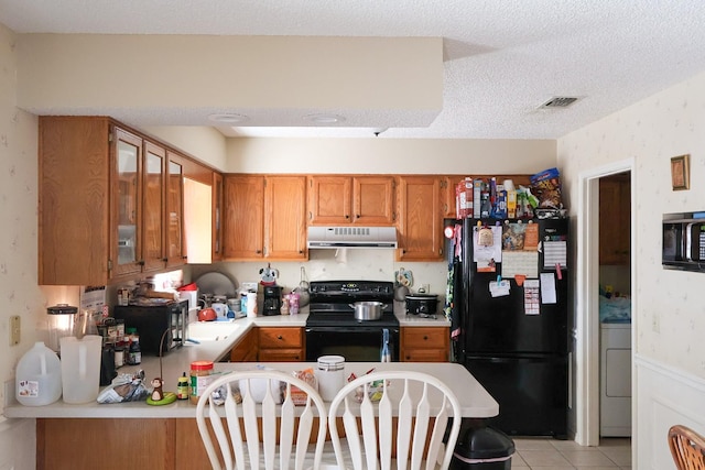 kitchen with a textured ceiling, light tile patterned floors, washer / clothes dryer, and black appliances