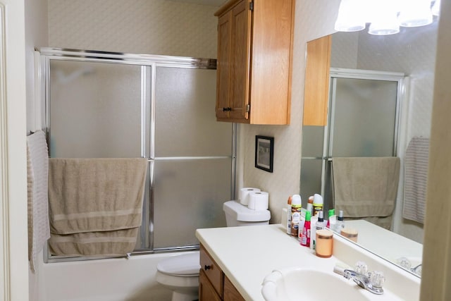 full bathroom featuring combined bath / shower with glass door, vanity, and toilet