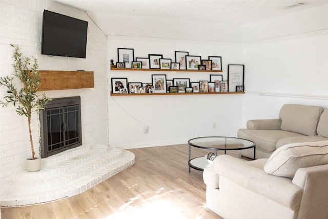 living room with a textured ceiling, a brick fireplace, lofted ceiling, and wood-type flooring