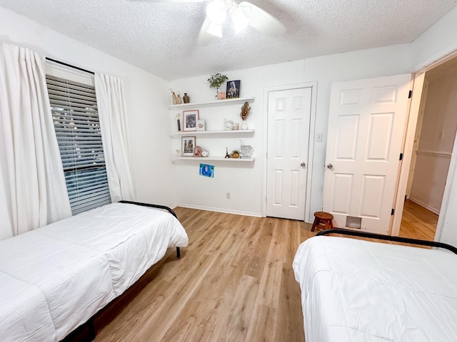 bedroom featuring ceiling fan, light wood-type flooring, and a textured ceiling