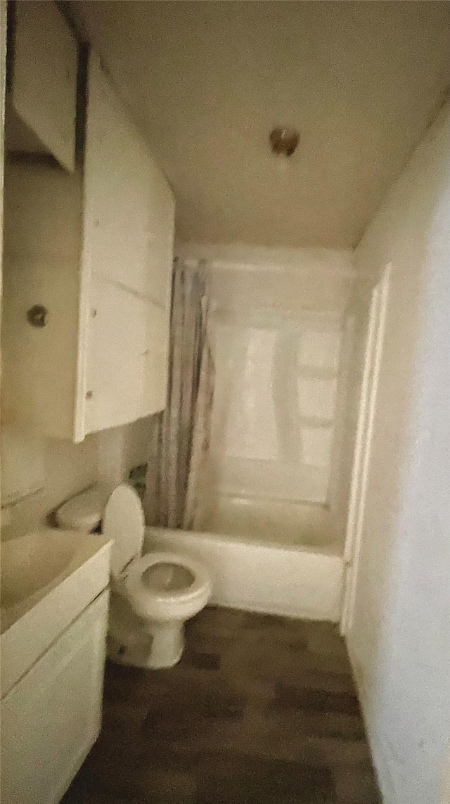 full bathroom featuring toilet, shower / bathtub combination with curtain, wood-type flooring, and vanity