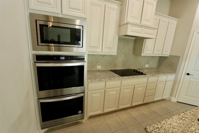 kitchen with appliances with stainless steel finishes, white cabinetry, decorative backsplash, and light stone counters