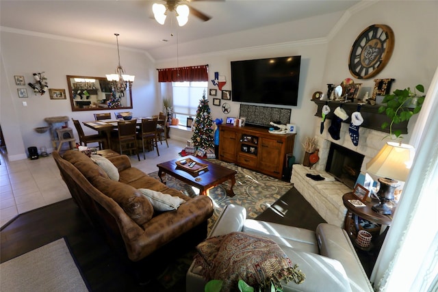 living room with tile patterned flooring, vaulted ceiling, ceiling fan with notable chandelier, and ornamental molding