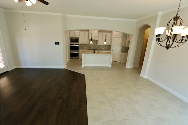 kitchen with decorative light fixtures, decorative backsplash, appliances with stainless steel finishes, open floor plan, and light stone countertops