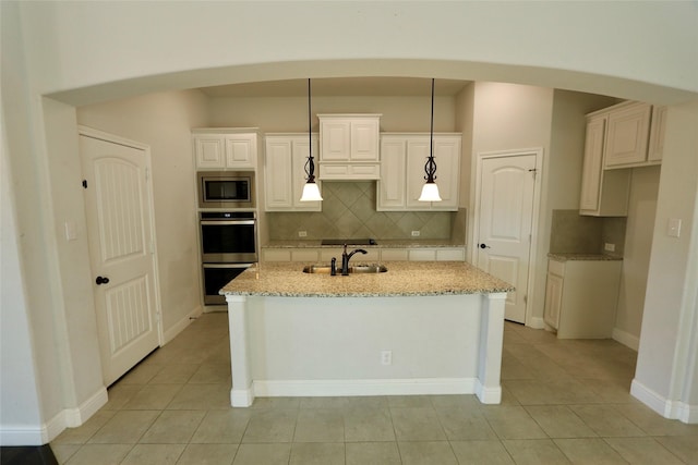 kitchen featuring arched walkways, appliances with stainless steel finishes, light stone counters, and decorative light fixtures