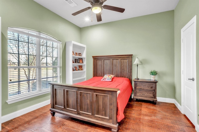 bedroom with ceiling fan, dark wood-type flooring, and multiple windows