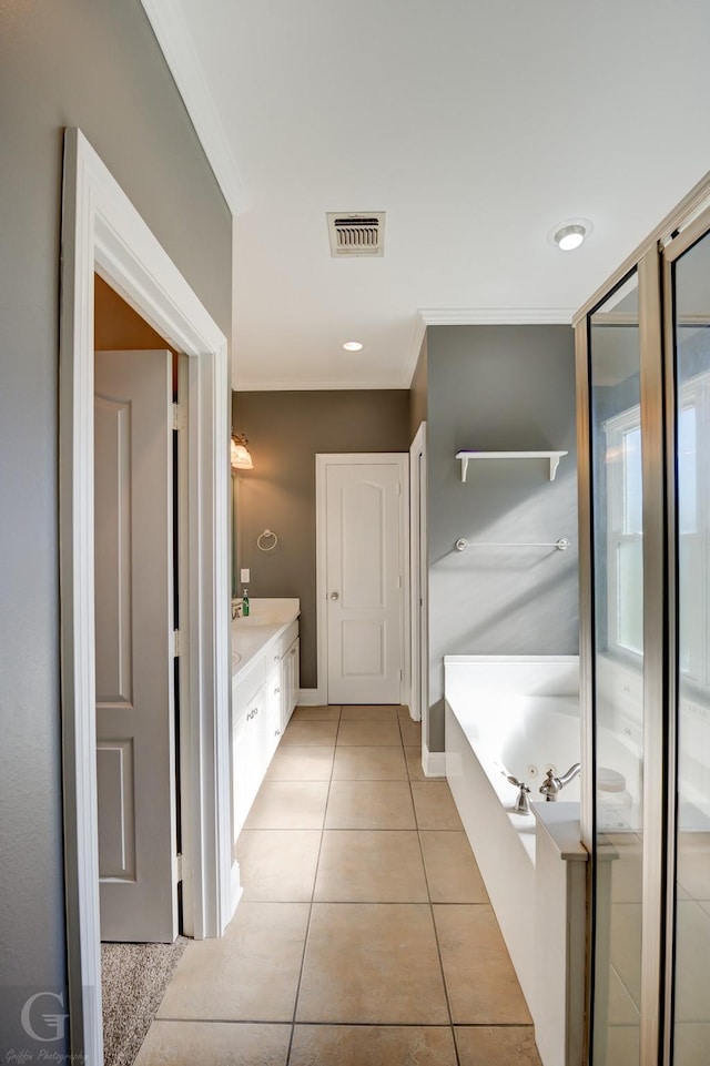 bathroom with a tub to relax in, vanity, tile patterned floors, and ornamental molding