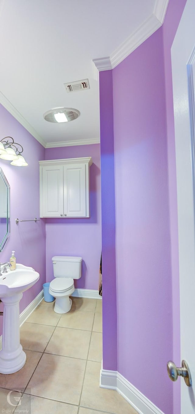 bathroom featuring tile patterned flooring, ornamental molding, and toilet