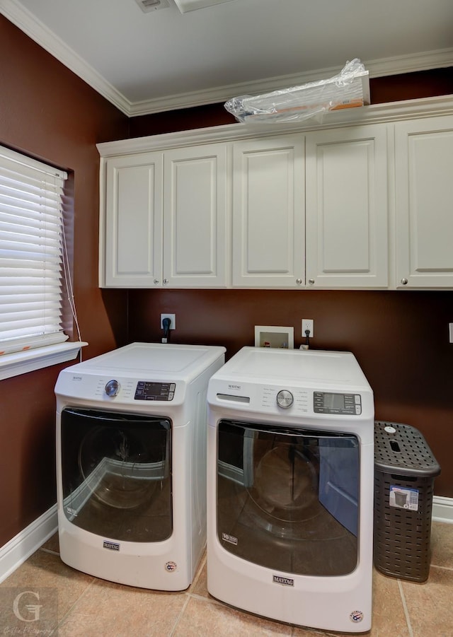 washroom with light tile patterned floors, ornamental molding, washing machine and dryer, and cabinets