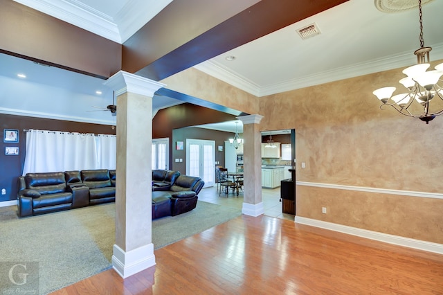 living room featuring hardwood / wood-style floors, crown molding, ceiling fan with notable chandelier, and decorative columns