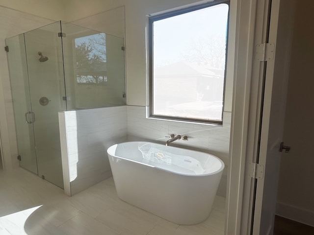 full bathroom featuring a freestanding bath, a stall shower, and tile walls