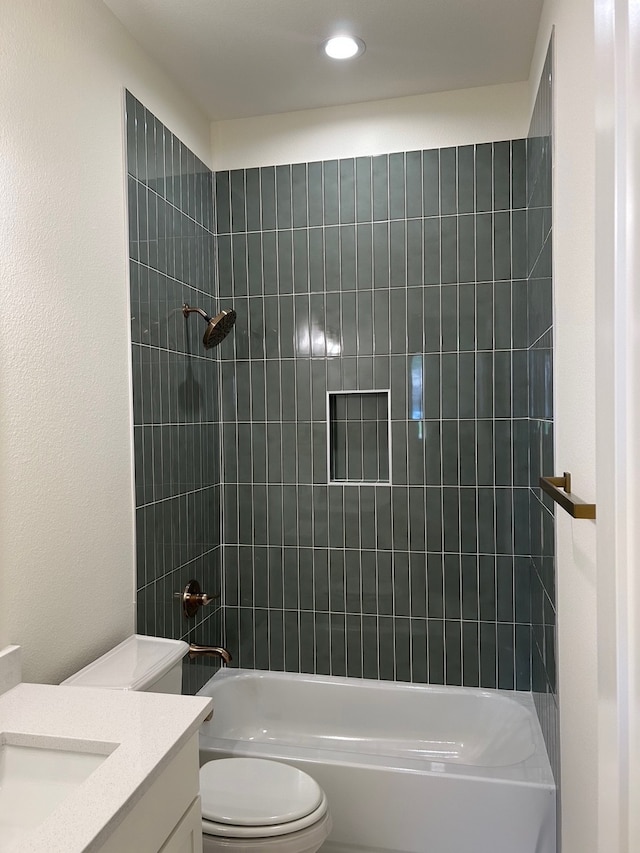 full bathroom featuring toilet, tiled shower / bath, and vanity