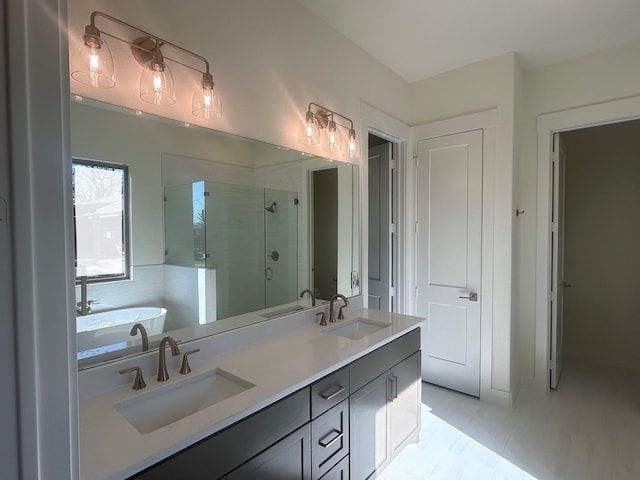 full bathroom with double vanity, a freestanding tub, a stall shower, and a sink