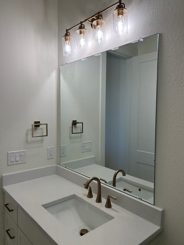 bathroom with a textured wall and vanity