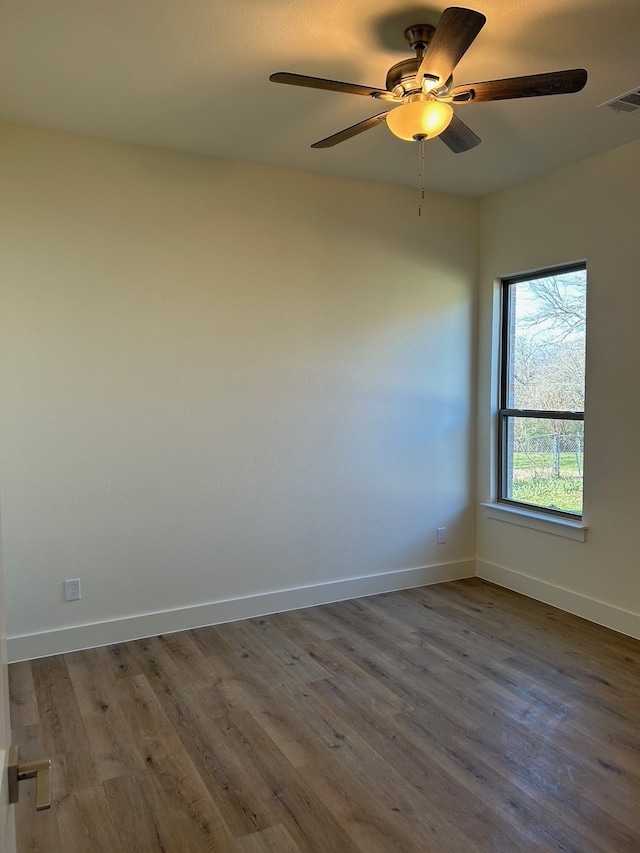 empty room featuring a ceiling fan, baseboards, visible vents, and wood finished floors