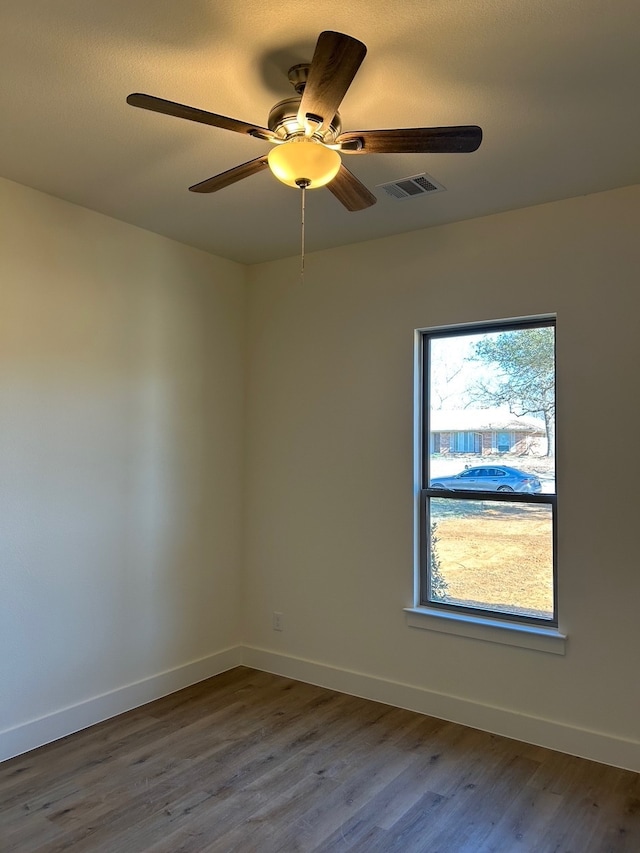 spare room featuring wood finished floors, visible vents, and baseboards